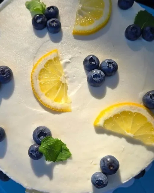 Top view of a white cake decorated with lemon slices, blueberries and mint