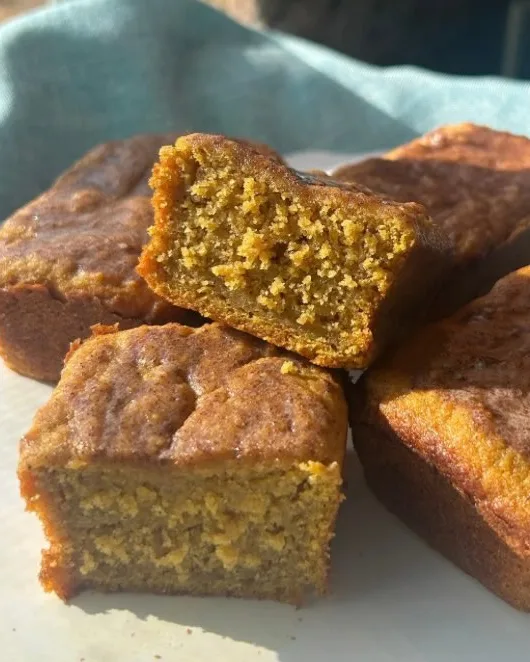 Mini pumpkin loaves stacked on a plate, one broken open