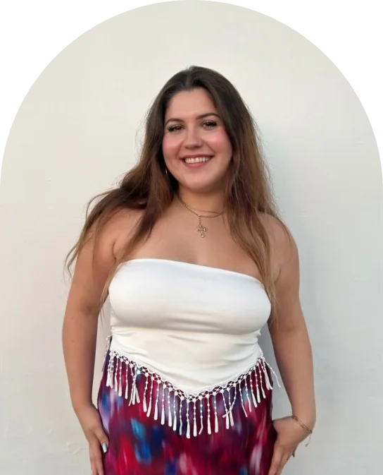 Selah, the baker behind Neli’s Oven, smiling in front of a white wall